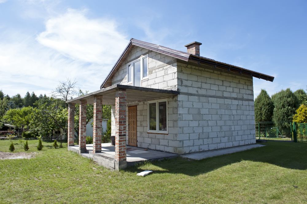 Недостроенный дачный домик из каменных блоков с крышей из металочерепицы.